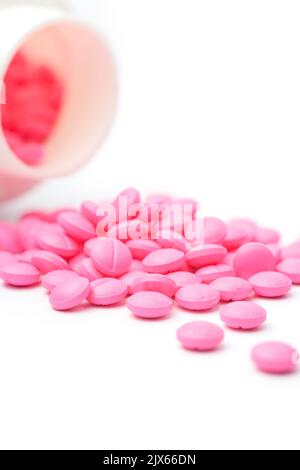 compresse o pillole rotonde rosa sparse su sfondo bianco dalla sua bottiglia o contenitore, farmaci presi soft-focus con spazio di copia Foto Stock