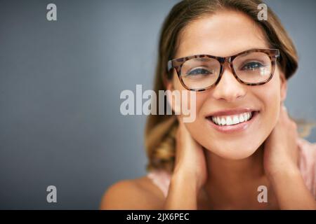 Con le sue caratteristiche eleganti e un sorriso spettacolare. Ritratto corto studio di una giovane donna attraente indossare occhiali. Foto Stock