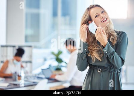 Donna d'affari, dipendente e lavoratore aziendale che rimuove la maschera di cocid in ufficio al lavoro, felice circa la fine della pandemia e dando il sorriso mentre lavora a. Foto Stock