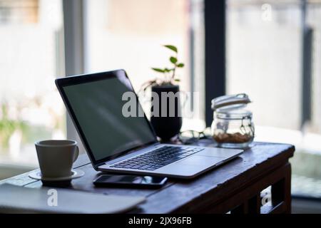 spazio di lavoro di un freelancer che lavora da casa con il portatile e il cellulare sul tavolo finale Foto Stock