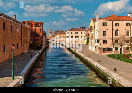 Vista dello stretto canale tra le tipiche vecchie case come la torre dell'Arsenale sullo sfondo a Venezia, Italia. Foto Stock