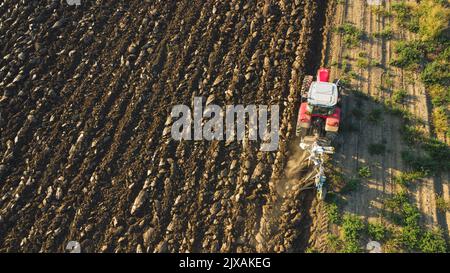 Vista aerea con drone di trattore che arava il terreno in campagna. Foto Stock