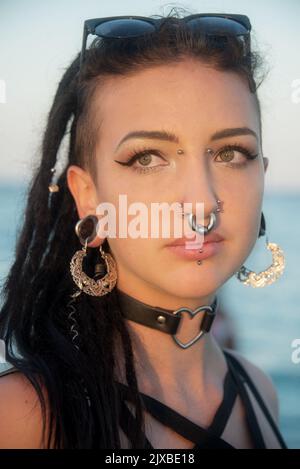 ritratto di sensibile giovane adolescente donna, ragazza con capelli scuri, greggi, molti piercing in faccia al tramonto estivo Foto Stock