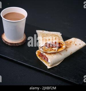 Tazza di tè piena di tè su un pezzo di legno Royalty Free Stock Foto, immagine, accanto hanno un gustoso shawarma Foto Stock