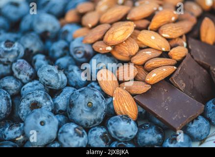 Mirtilli freschi, biologici e maturi, miscelati con mandorle secche non salate e pezzi di cioccolato fondente Foto Stock