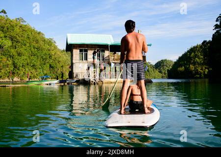 Giovane coppia in canoa nella laguna al mattino, godendo la vista. Sugba Bay a Siargao, Filippine Foto Stock