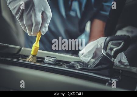 Primo piano dello strumento di dettaglio automatico professionale per la pulizia degli interni che viene utilizzato dal dettagliante del veicolo per rimuovere la polvere dai controller intorno al tran automatico Foto Stock