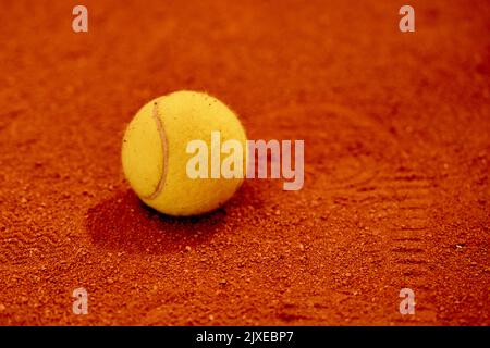 Palla da tennis gialla adagiata sulla linea del campo rosso e verde. Vista con disposizione piatta. Spazio per il testo Foto Stock