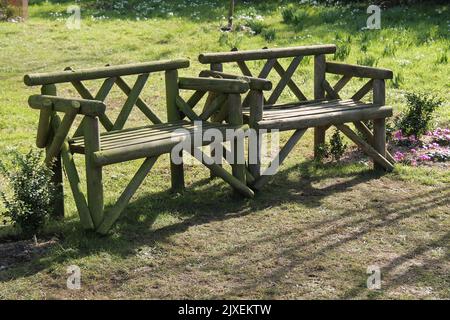 Due poltrone rustiche in legno in un giardino. Foto Stock