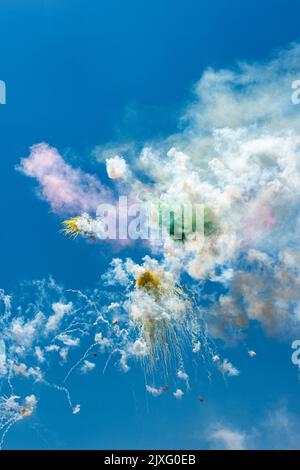 I fuochi d'artificio esplodono alla luce del sole contro un cielo blu segnano una festa religiosa in un villaggio siciliano Foto Stock