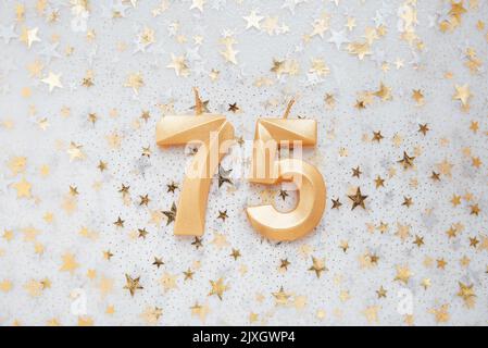 Numero 75 settantacinque candela d'oro per festeggiare il compleanno su sfondo festivo. Settantacinque anni di compleanno. Concetto di celebrare il compleanno, l'anniversario, la data importante, la festa Foto Stock