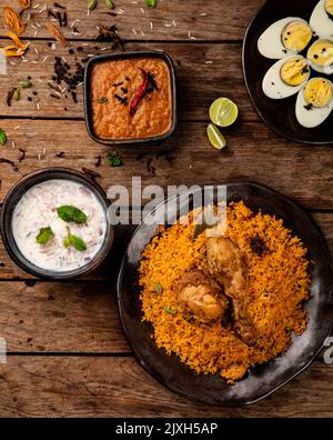 Pollo Biryani piatto indiano che viene fornito in un set di cibo a base di riso fatto con spezie, riso e pollo e servito con sugo di carne e uvetta di cipolla Foto Stock