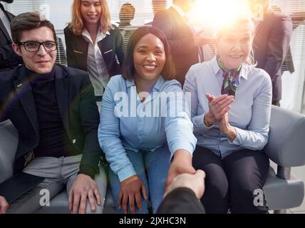 Felice multi-etnico collaboratori handshaking in ufficio Foto Stock