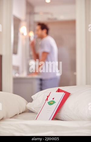 San Valentino Card sul letto come l'uomo Brushes denti in background Foto Stock