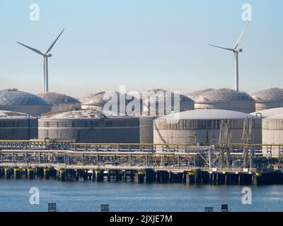 Il passato e il futuro dell'approvvigionamento energetico: Turbine eoliche e enormi serbatoi di stoccaggio del petrolio fuori da Rotterdam, nei Paesi Bassi. Il porto di Rotterdam è la Foto Stock