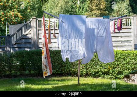 Abiti appesi su scaffale per asciugare all'aperto in cortile in estate Foto Stock