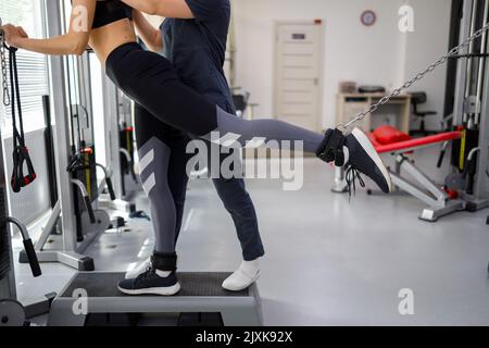 La cinesiologa aiuta una donna a fare esercizi per rafforzare i suoi muscoli. Il medico riabilitativo aiuta il paziente a riprendersi dalle lesioni Foto Stock