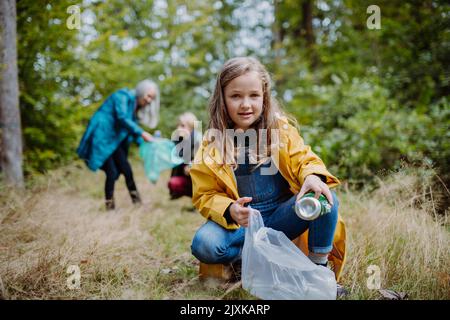 Bambina con madre e nonna che raccoglie i rifiuti outoors nella foresta. Foto Stock