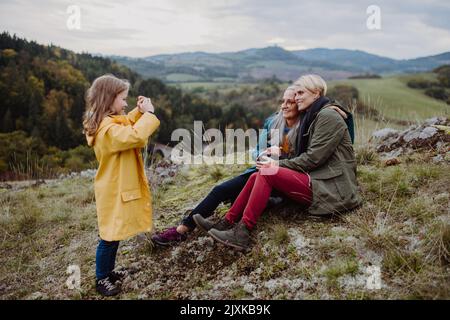 Piccola ragazza con madre e nonna che scattano foto outoors in cima alla montagna. Foto Stock