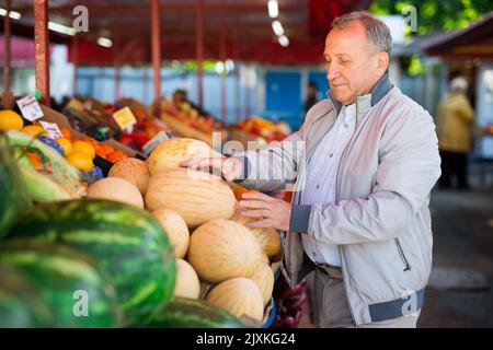 Uomo di mezza età che acquista melone Foto Stock