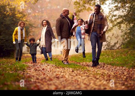 Famiglia Multi-Generation sorridente divertirsi con i bambini camminare insieme attraverso la campagna autunnale Foto Stock
