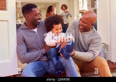 Nonno con il padre e il figlio siediti sul punto nel paese che mette sugli stivali prima di andare sulla camminata della famiglia Foto Stock