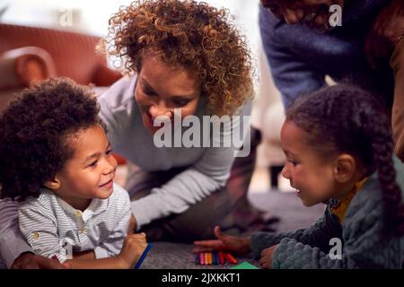 Nonni a casa con nipoti disegnare immagini in Lounge insieme Foto Stock