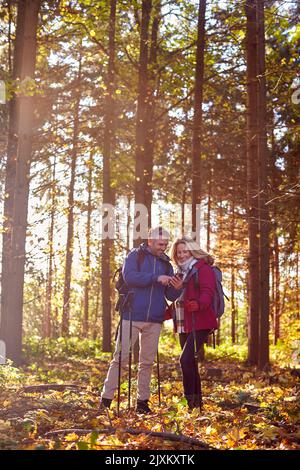 Una coppia matura in pensione cammina in autunno o in inverno nella campagna utilizzando la mappa o l'app di navigazione sul telefono cellulare Foto Stock