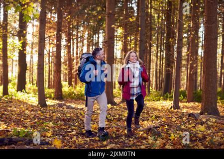 Coppia matura in pensione con zaini che camminano attraverso la campagna autunnale o invernale Foto Stock