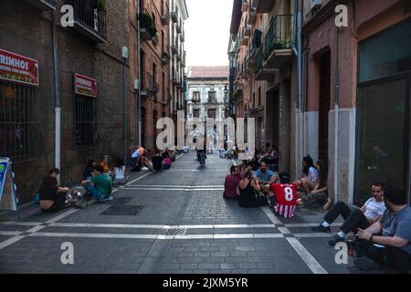 Pamplona, Spagna - Luglio, 30: Gruppo di giovani felici seduti sul pavimento bere birra. Gli amici godono il tempo piacevole insieme, divertendosi al h Foto Stock