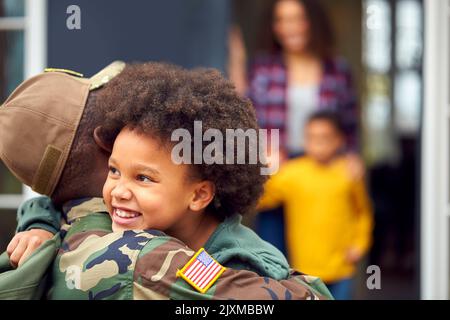 Soldato americano in uniforme ritorno a casa in famiglia sul abbraccio bambini fuori casa Foto Stock