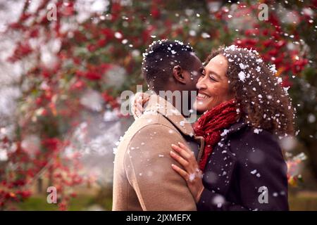Coppia affettuosa che abbraccia e si diverta a passeggiare in autunno o in inverno in campagna nella neve Foto Stock