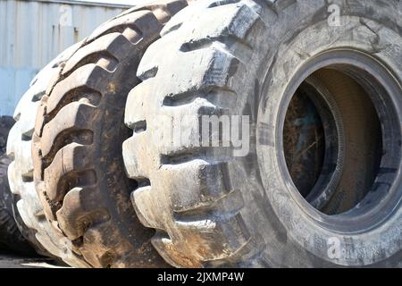 Riga, Lettonia - 13 maggio 2022: Pneumatici usati molto grandi per camion impilati per il riciclaggio. Inquinamento industriale dell'ambiente. Foto Stock