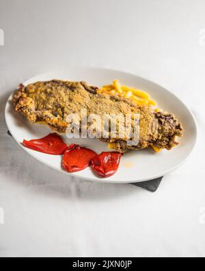 Cachopo con pepe rosso e patatine fritte, tipico pasto asturiano Foto Stock