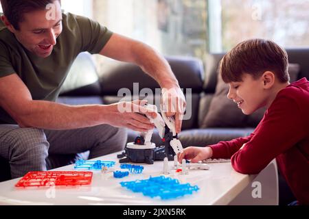 Padre e Figlio indossano pigiami costruendo braccio robotico da Kit di plastica a casa Foto Stock