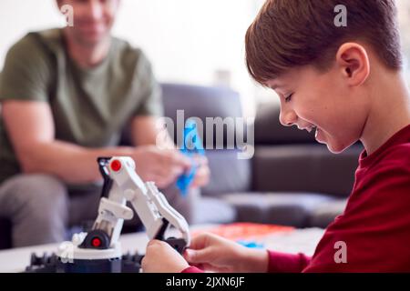 Padre e Figlio indossano pigiami costruendo braccio robotico da Kit di plastica a casa Foto Stock