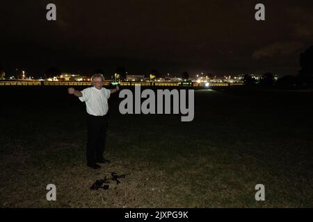 Un uomo è visto con le mani in su come la polizia si avvicina attraverso il tratto di erba vicino all'aeroporto di Heathrow. Un drone e un microtelefono possono essere visti ai suoi piedi. Foto Stock