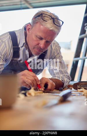 Maturo maschio falegname in officina Garage marcatura legno con matita e righello in acciaio Foto Stock