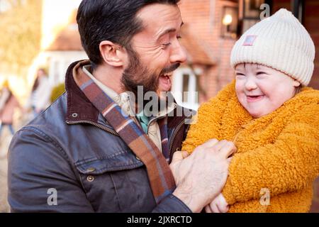 Famiglia con Down Syndrome figlia prepararsi a andare per l'autunno o inverno camminare insieme Foto Stock