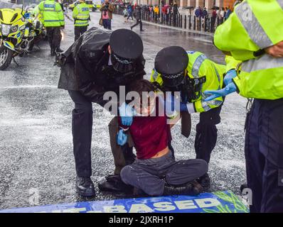 Londra, Regno Unito. 7th Set, 2022. La polizia arresta un attivista. Gli attivisti della ribellione animale hanno coperto il muro fuori dal Parlamento con vernice bianca, simboleggiando il latte, e bloccato la strada che porta al Westminster Bridge davanti ai primi PMQ di Liz Truss. L'azione faceva parte della campagna in corso del gruppo per i diritti degli animali contro i prodotti lattiero-caseari, che chiedeva un futuro basato sulle piante. Credit: Vuk Valcic/Alamy Live News Foto Stock