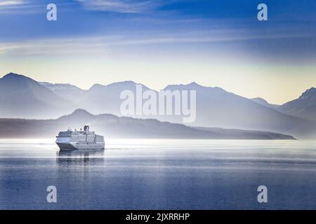 Una nave da crociera che naviga un fiordo in Alaska in una serata estiva Foto Stock