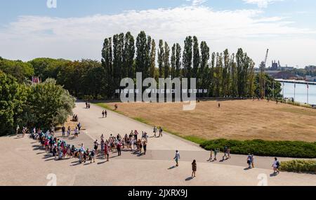 Un'immagine del segno polacco che recita come 'No More War' a Westerplatte, accanto a un gruppo di bambini in una gita sul campo. Foto Stock