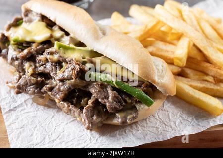 Sandwich di cheesesteak Philly con manzo, formaggio, peperoni verdi e cipolla caramellata isolata su sfondo bianco. Tradizionale sandwich di philadelphia Foto Stock