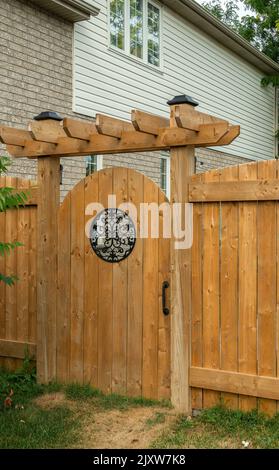 Porta in legno con finestra rotonda all'ingresso del cortile di una casa privata Foto Stock