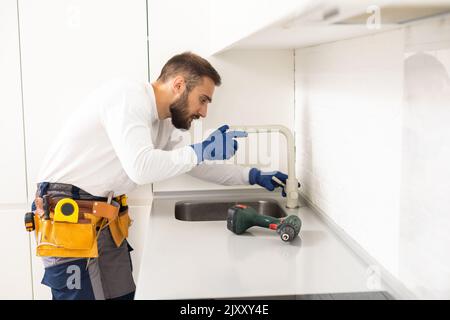 idraulico installa rubinetto cucina. ristrutturazione in appartamento. Foto Stock