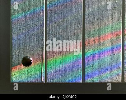 Strisce di luce colorata sulla vecchia porta dell'armadio in legno Foto Stock