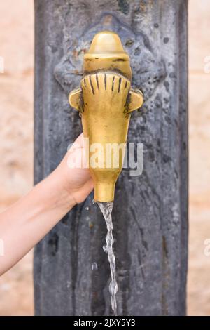 L'acqua potabile fresca e pulita fluisce da un rubinetto esterno quando un bambino accende il rubinetto Foto Stock