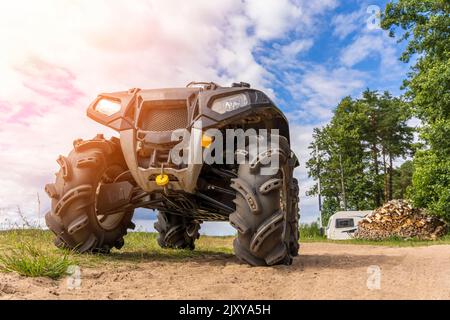 ATV sulla riva sabbiosa del lago sullo sfondo del campo Foto Stock