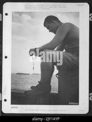 Un membro del 1878Th Engineer Aviation Battaglione che è in rotta per Okinawa, Ryukyu Retto, a bordo Di Un lst (Landing Ship Tank) dice il suo Rosario. 1945 Foto Stock