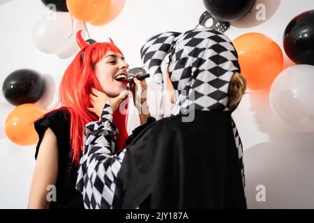 Amici in costume che si mettono a vicenda trucco ad una festa di Halloween Foto Stock